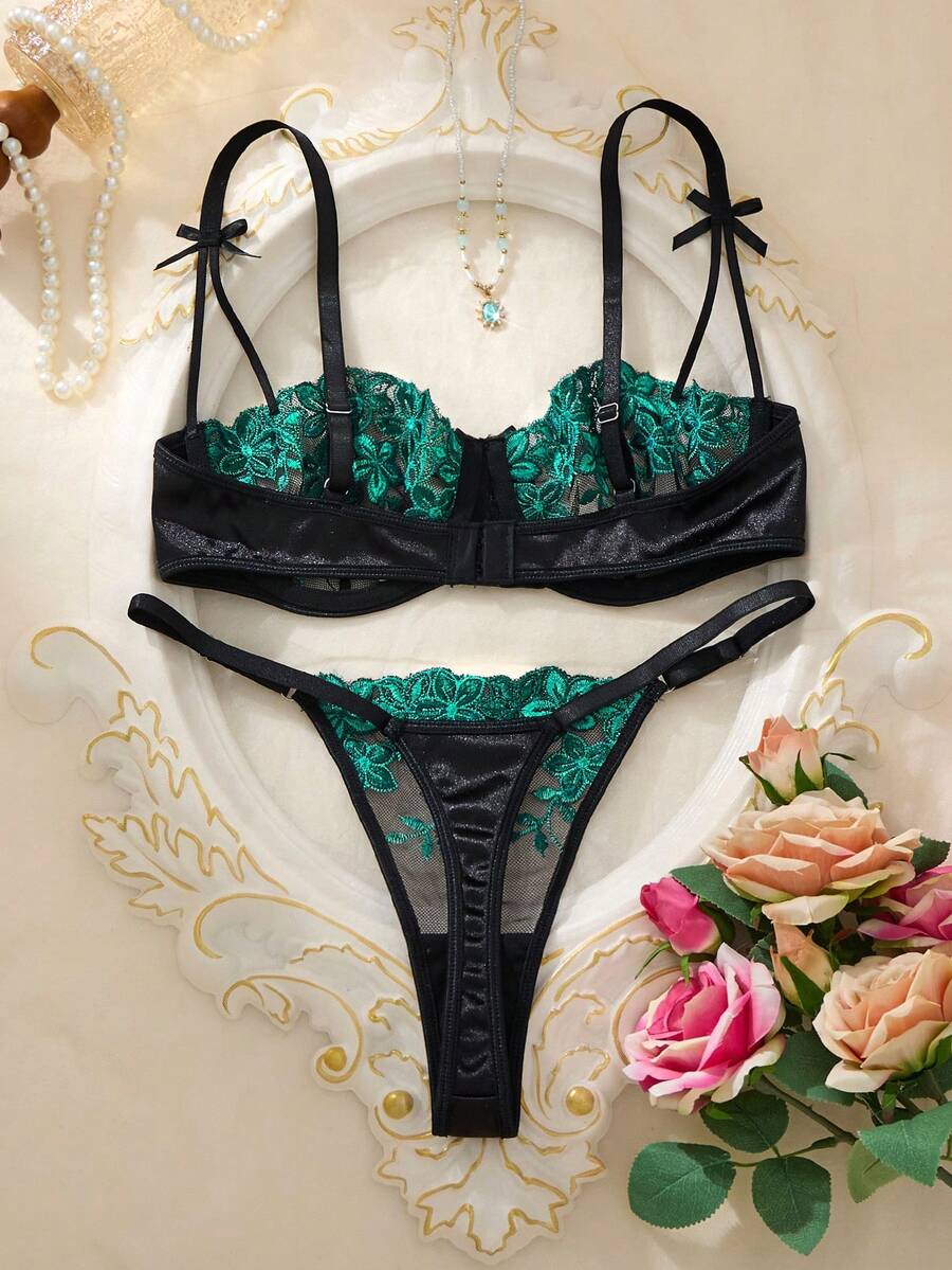 Conjunto de lencería negro con bordado floral verde esmeralda.