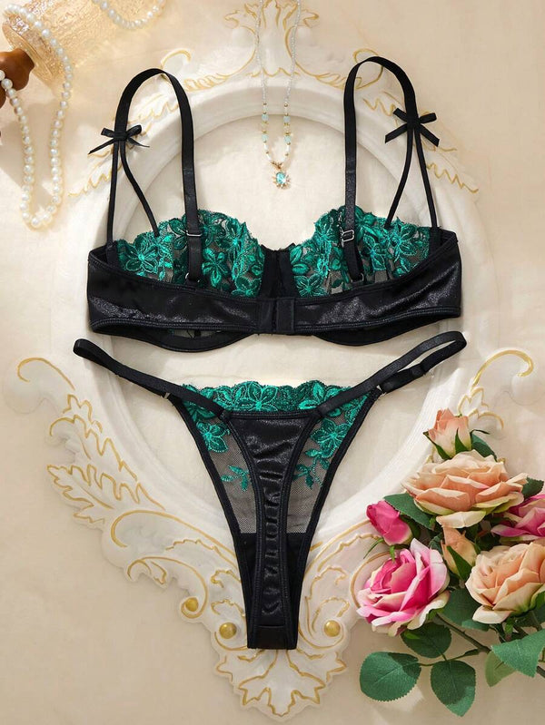 Detalle del sujetador con bordado floral verde y lazo en el tirante.