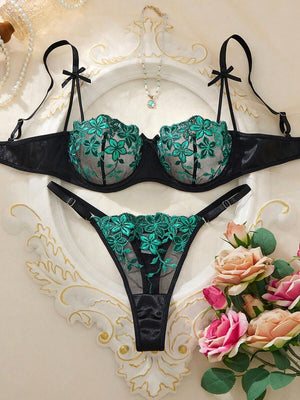 Vista frontal de la tanga negra con bordado floral verde en tul transparente.