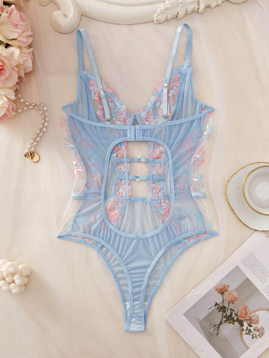 Body de lencería celeste con encaje floral rosa y azul sobre una percha.