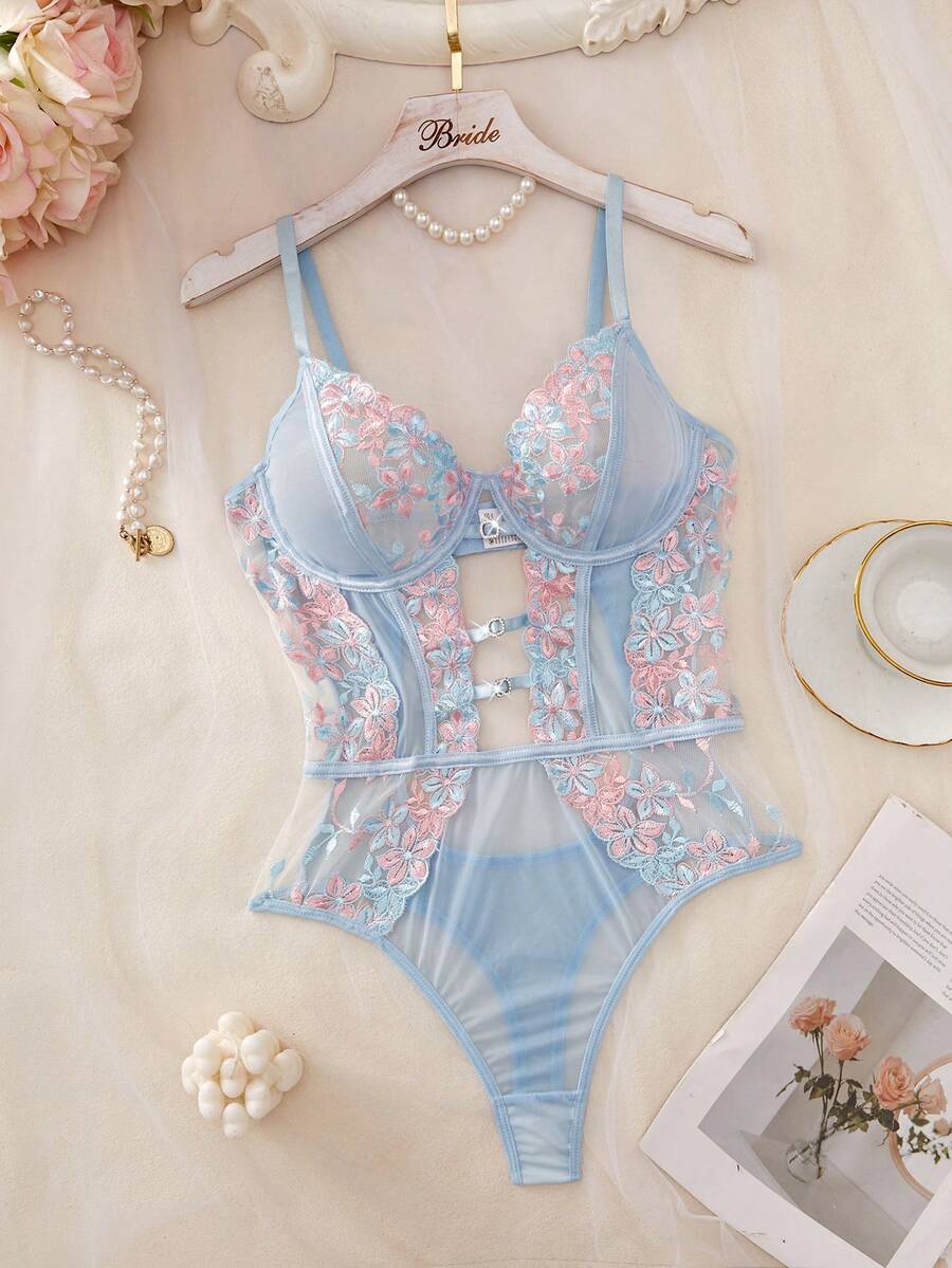 Body de lencería celeste con encaje floral rosa y azul sobre una percha.