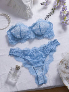 Conjunto de lencería de encaje floral color celeste sobre una superficie blanca.