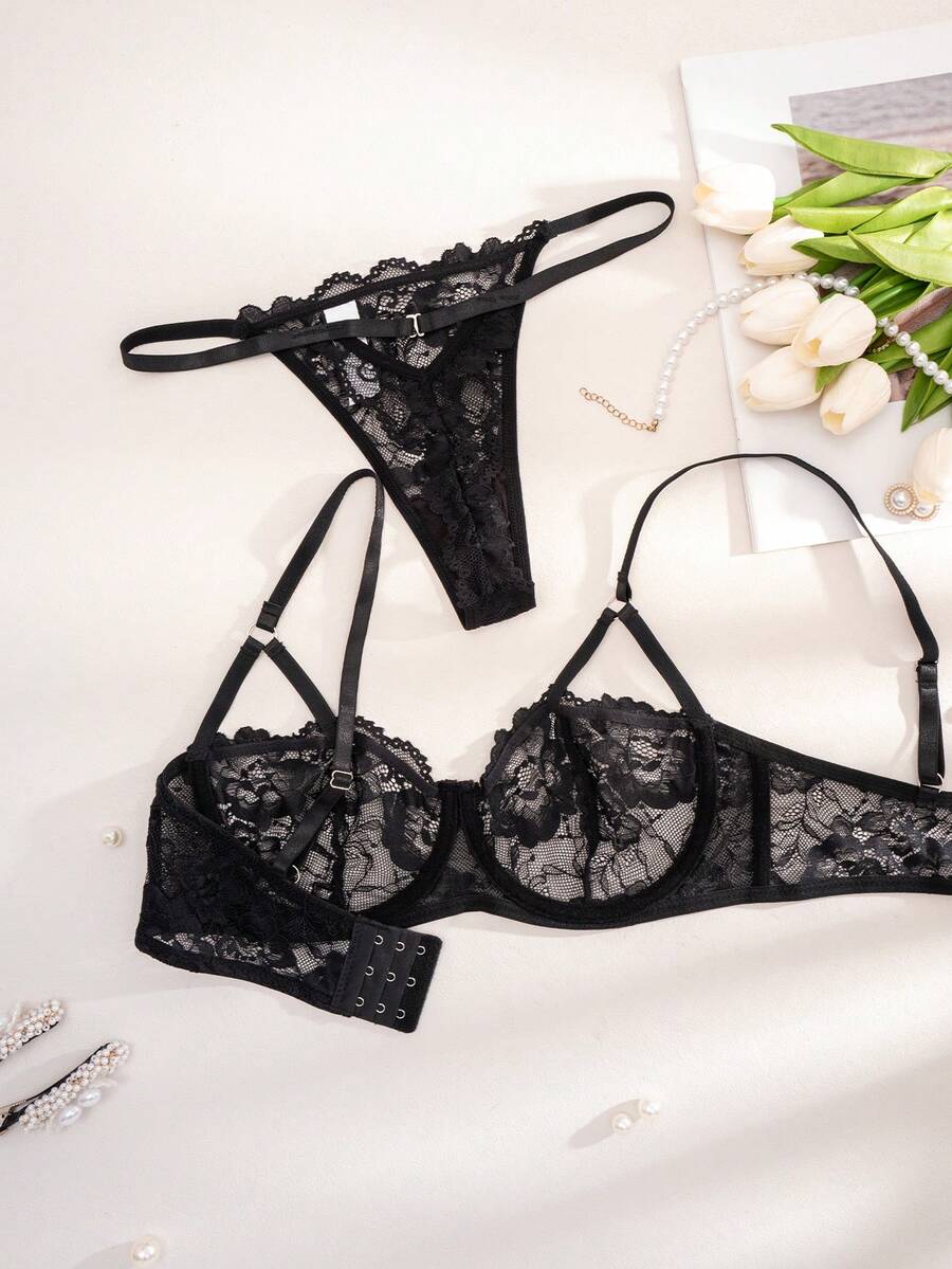 Conjunto de lencería de encaje negro con bra y tanga sobre fondo claro.