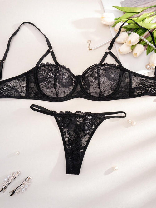 Conjunto de lencería de encaje negro con bra y tanga sobre fondo claro.