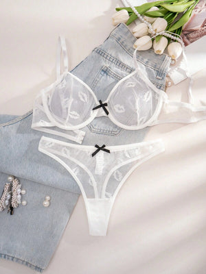 Vista frontal de la tanga de malla blanca a juego con estampado de labios y un pequeño lazo negro en el centro.