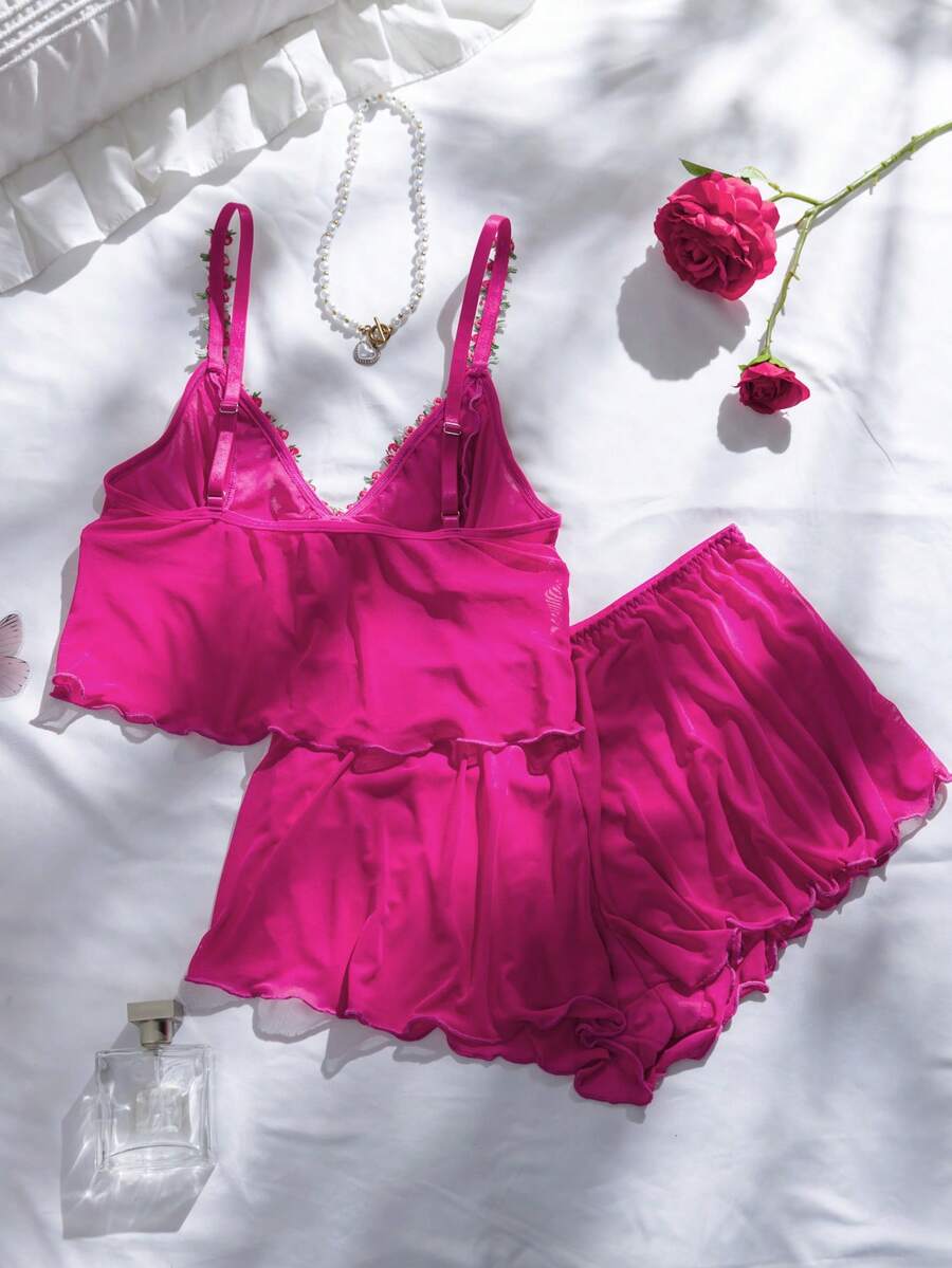 Modelo luciendo conjunto de lencería romántico de dos piezas color fucsia frente a un espejo.