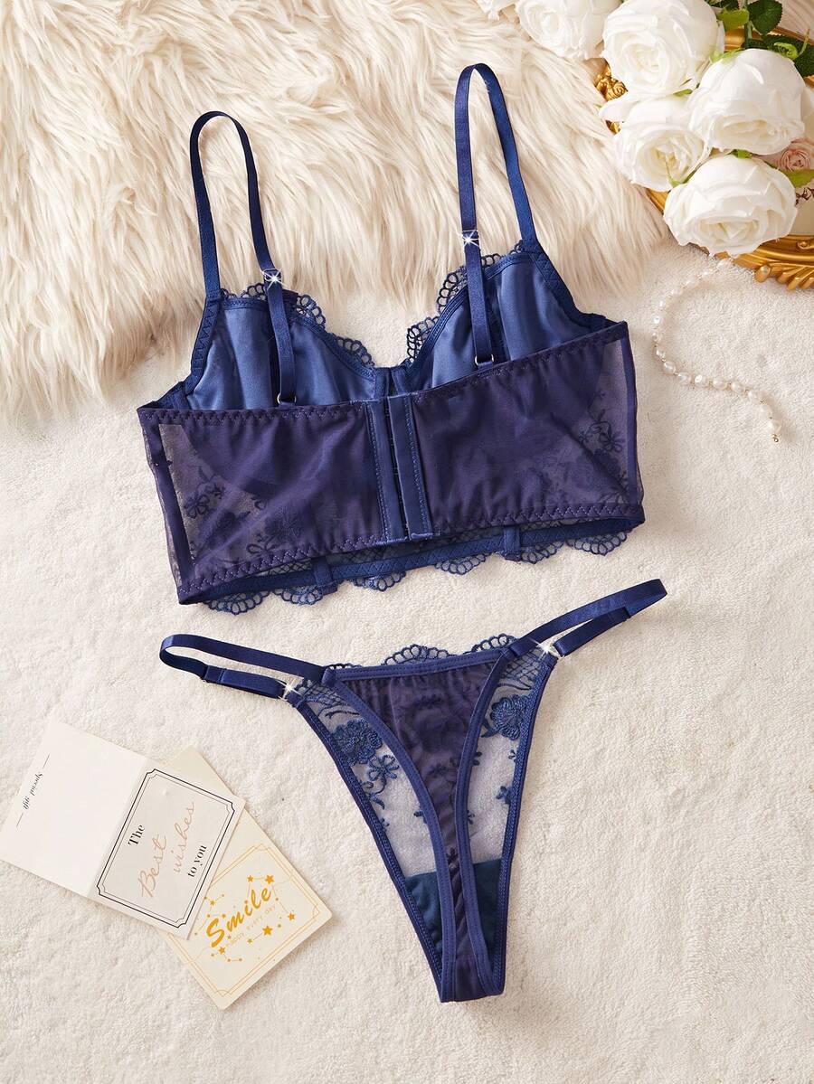 Conjunto de lencería de encaje floral azul marino sobre una superficie de felpa blanca.