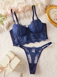 Conjunto de lencería de encaje floral azul marino sobre una superficie de felpa blanca.