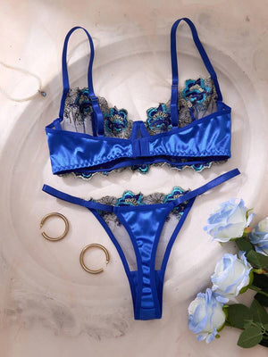 Detalle del brasier de lencería azul con copa de tul semitransparente y bordado floral detallado.