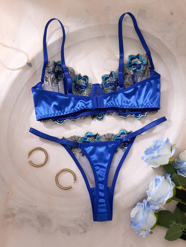 Detalle del brasier de lencería azul con copa de tul semitransparente y bordado floral detallado.