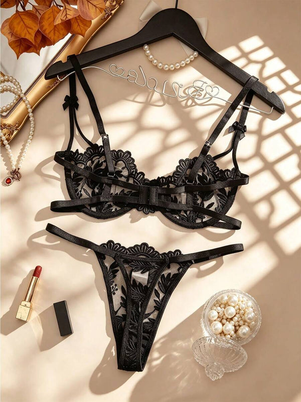 Detalle del brasier de encaje negro con bordado de hojas y tirantes con lazos.