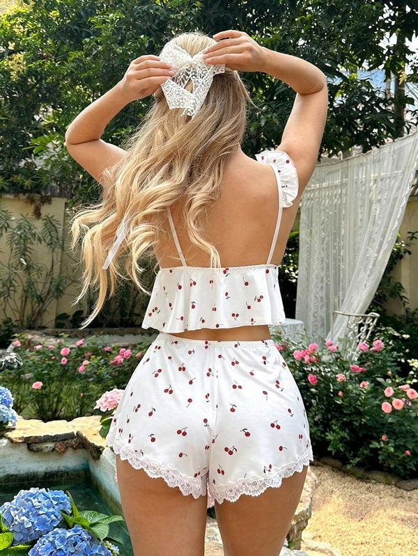 Vista trasera de una mujer luciendo un conjunto de pijama blanco con estampado de cerezas y un lazo de encaje en el cabello.