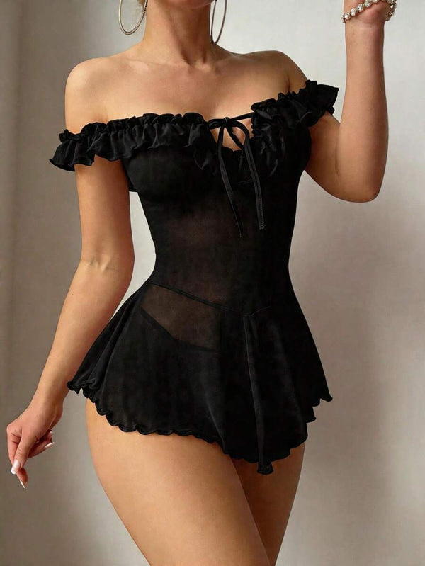Primer plano de la falda con vuelo de un babydoll negro, mostrando la tela de malla transparente y el dobladillo ondulado.