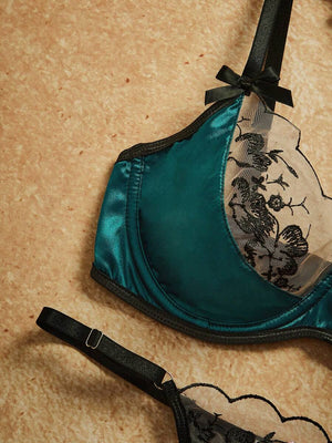 Detalle de la tanga del conjunto de lencería, destacando el panel de satín verde y el encaje floral negro.