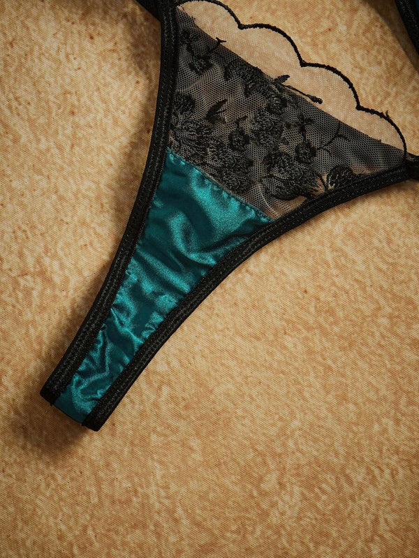 Vista superior del conjunto completo de brasier y tanga de lencería sobre una superficie texturizada.