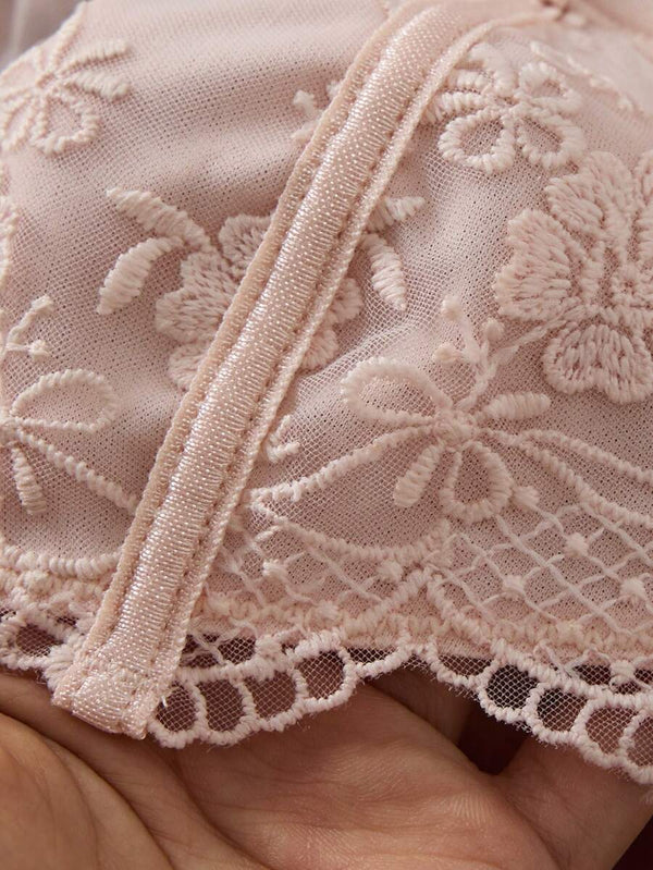 Vista de cerca de la tanga de lencería rosa con encaje floral y transparencias en la parte delantera.