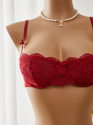 Vista de cerca de la tanga de encaje rojo con detalle floral transparente y lazo lateral de satén.