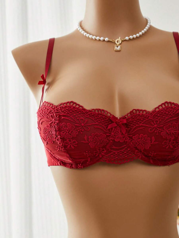 Vista de cerca de la tanga de encaje rojo con detalle floral transparente y lazo lateral de satén.