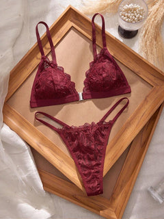 Conjunto de lencería de encaje floral color burdeos sobre un marco de madera.