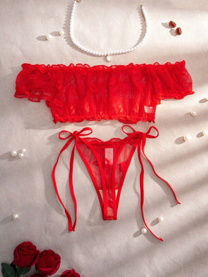 Vista frontal de la tanga de lencería roja con diseño de lazos laterales.