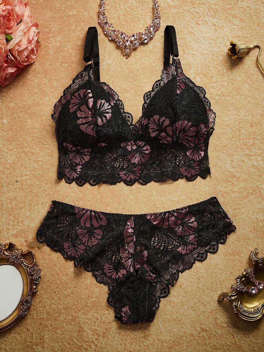 Conjunto de lencería de encaje negro con flores lilas en vista superior sobre un fondo neutro.