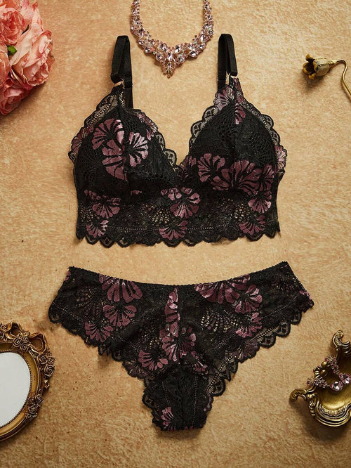 Conjunto de lencería de encaje negro con flores lilas en vista superior sobre un fondo neutro.