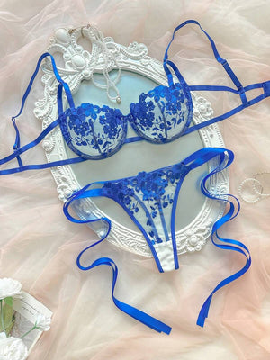Conjunto de lencería romántico con bordado floral azul sobre una base de tul transparente.