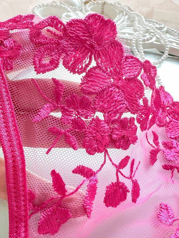 Vista detallada de la tanga de lencería rosa fucsia con encaje floral transparente.