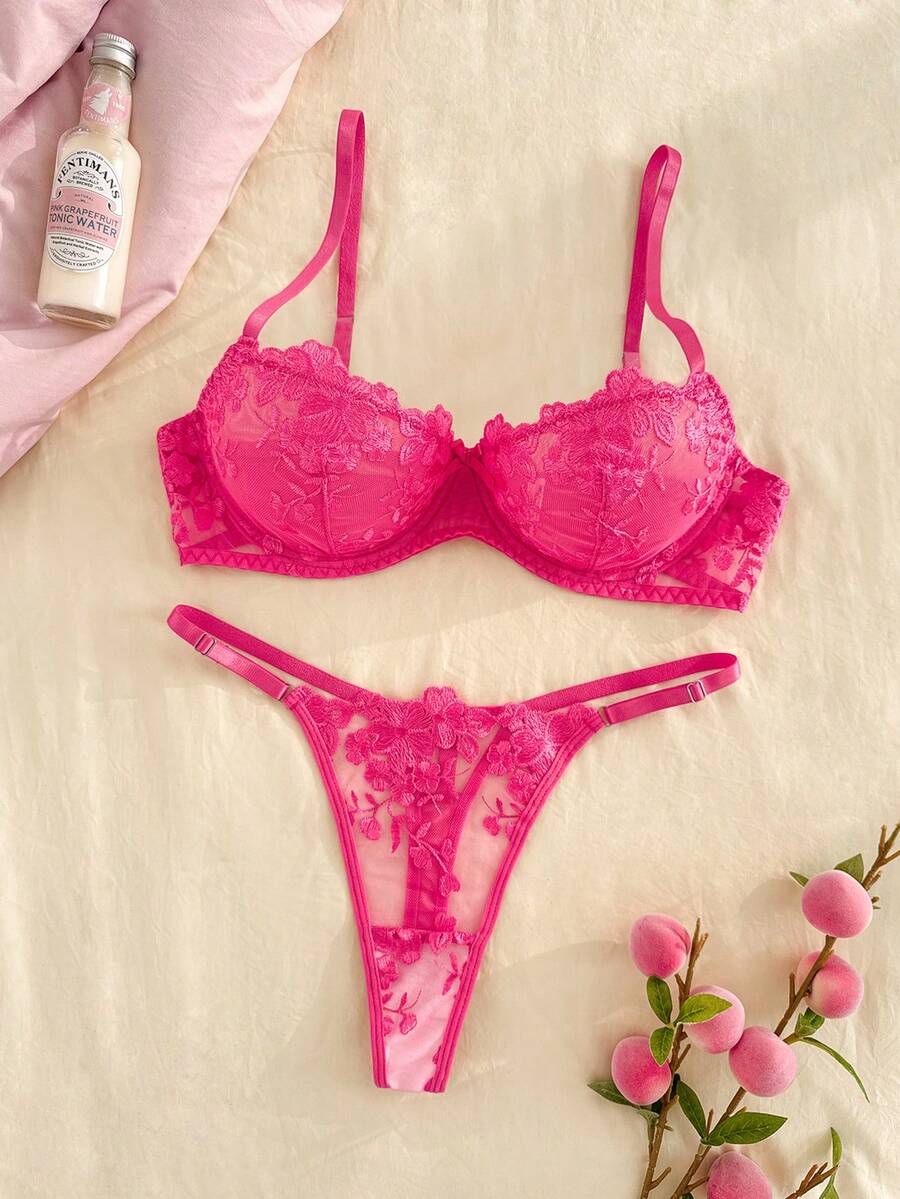 Conjunto de lencería fucsia con bordado floral visto desde arriba sobre una superficie clara.