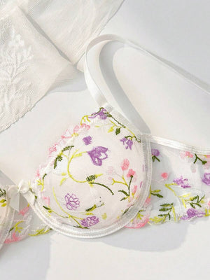 Primer plano de las copas del sujetador de malla transparente con flores bordadas.