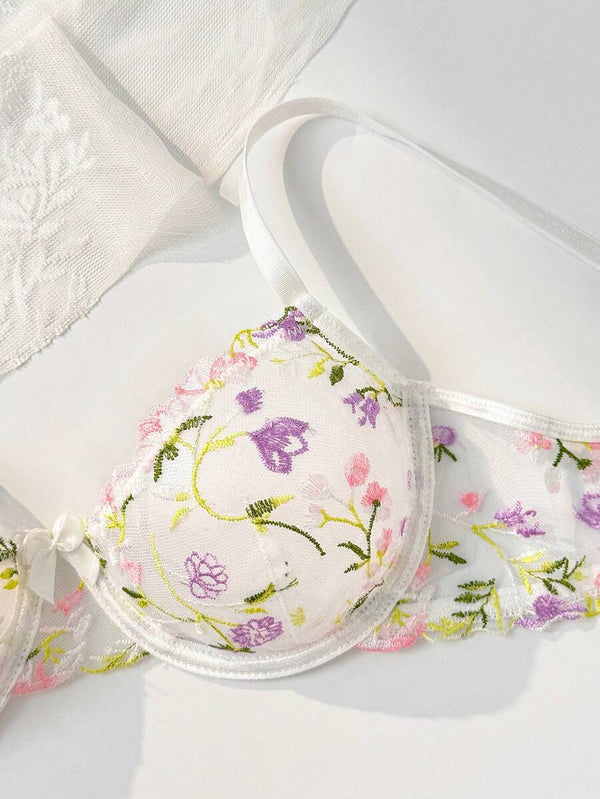 Primer plano de las copas del sujetador de malla transparente con flores bordadas.