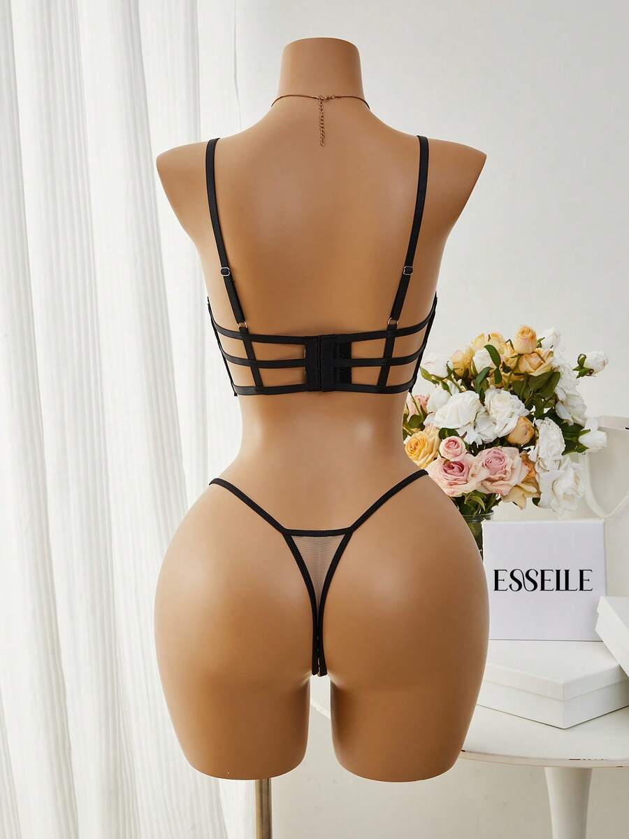 Vista frontal de un conjunto de lencería de dos piezas en un maniquí, con bordado floral negro sobre una base de malla beige.