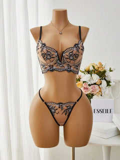 Vista frontal de un conjunto de lencería de dos piezas en un maniquí, con bordado floral negro sobre una base de malla beige.