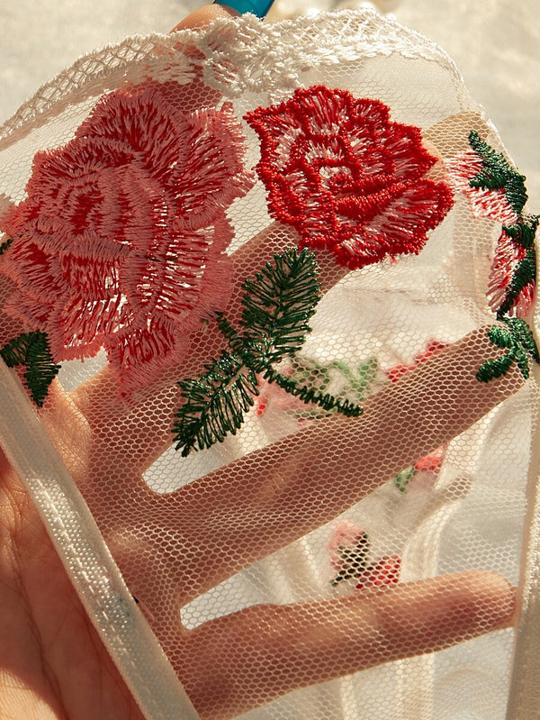 Vista completa del conjunto de brasier y tanga blancos con bordado de rosas y aplicaciones florales