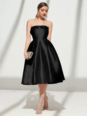 Vista completa de una modelo luciendo un vestido de cóctel negro strapless con falda midi voluminosa.