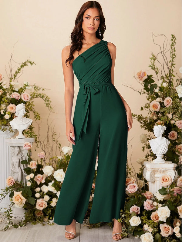 Modelo posando con el mono largo verde oscuro elegante en un entorno floral.