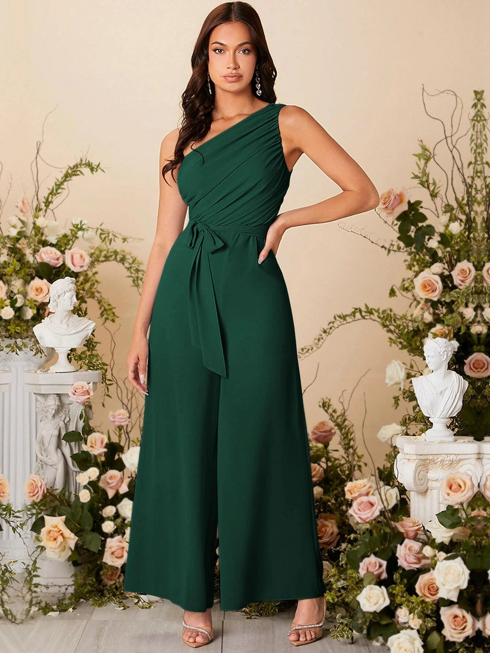 Modelo con mono largo verde oscuro elegante con cuello asimétrico y cinturón.