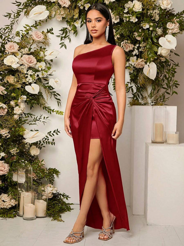 Vestido burdeos asimétrico con abertura alta en pose elegante.