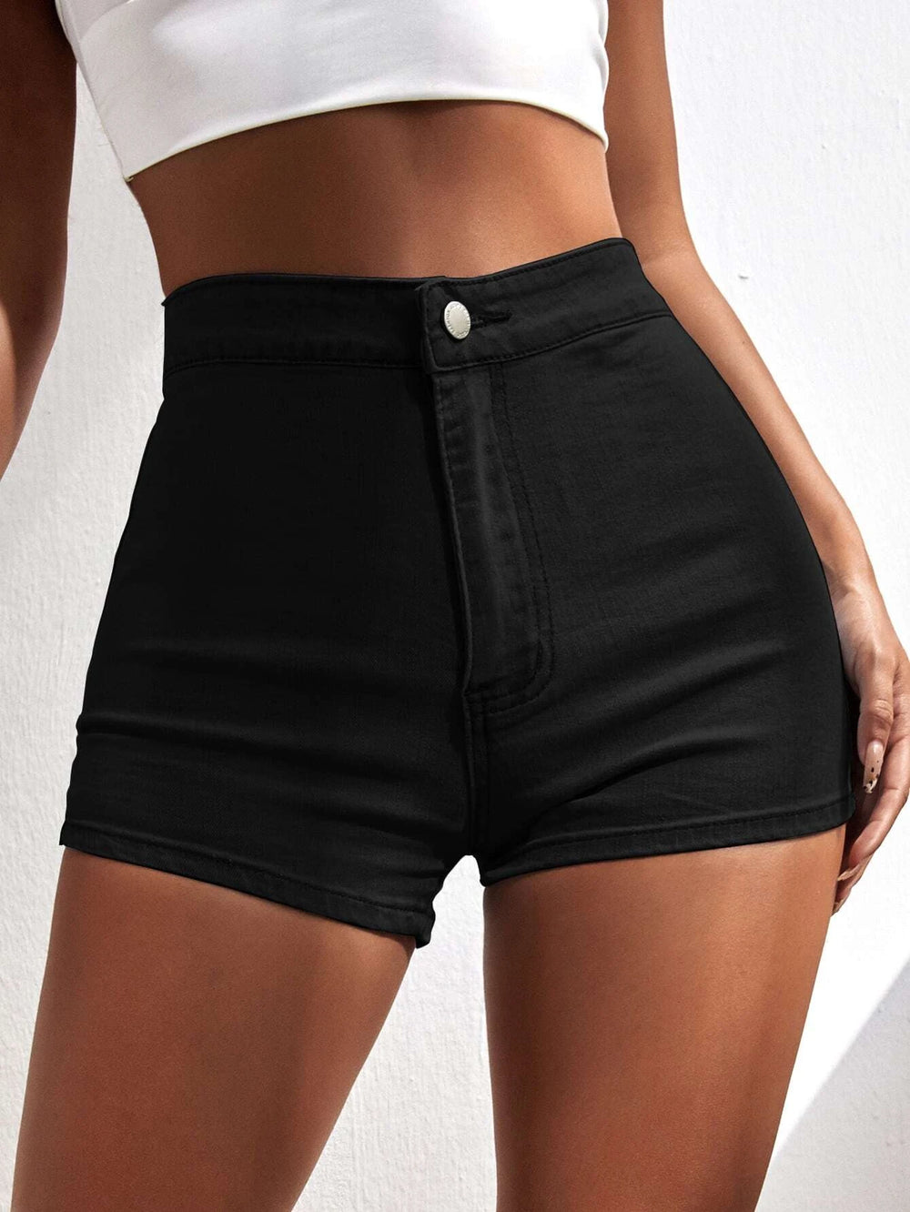 Modelo con short negro de mezclilla de tiro alto en fondo blanco