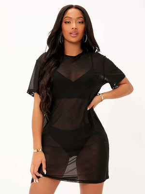 Vista frontal de una mujer usando un vestido de malla transparente negro sobre un conjunto de lencería.