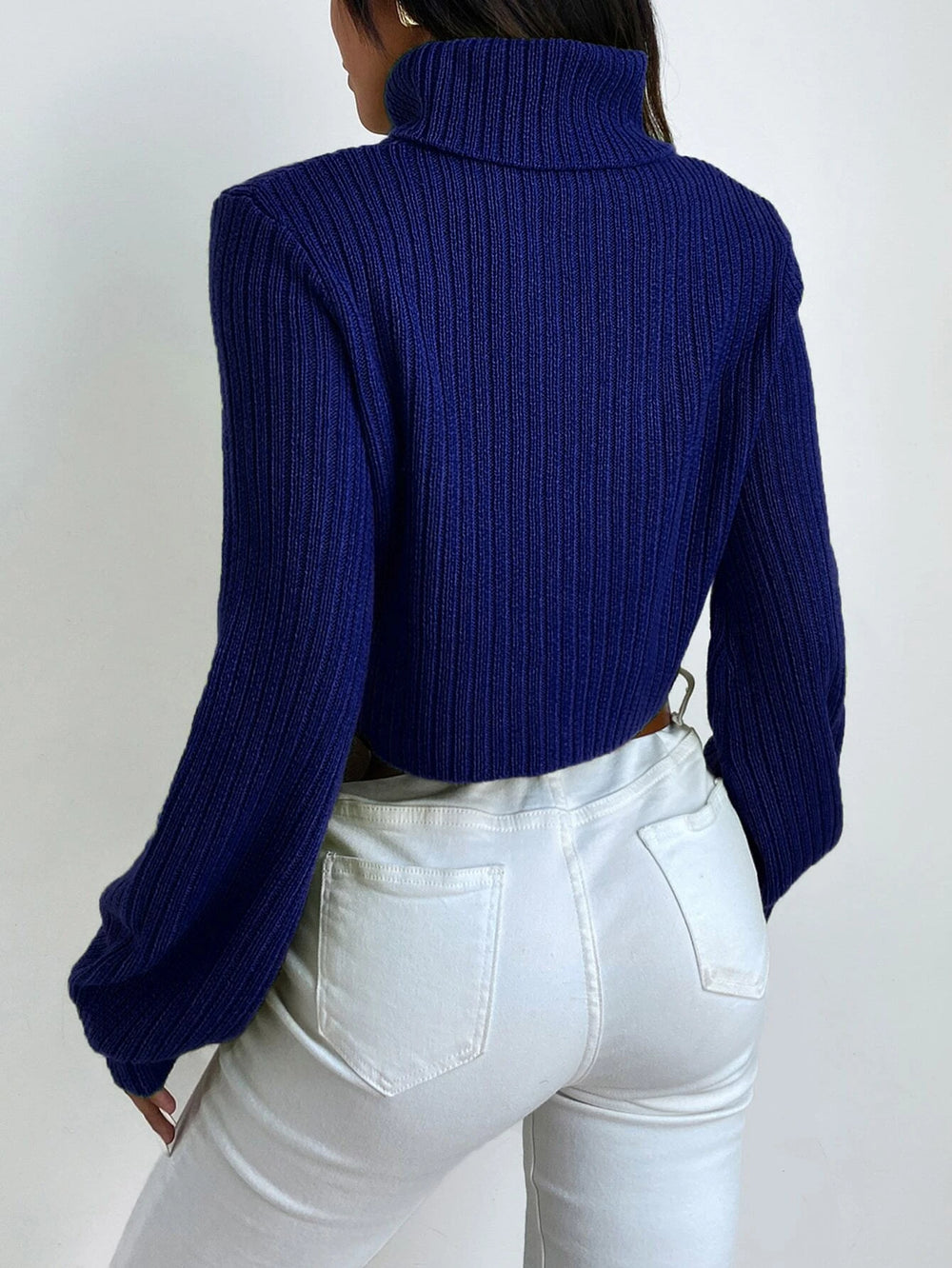 Vista lateral del suéter azul real con cuello cisne y manga obispo.