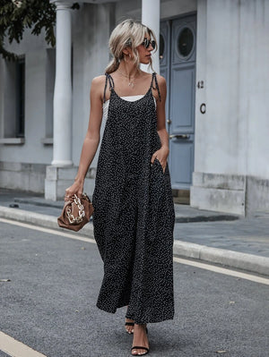 Mujer caminando en la calle con un jumpsuit negro de lunares blancos, tirantes anudados y bolsillos.