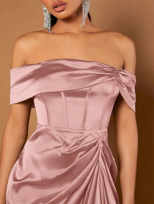 Vista de perfil de las piernas de una modelo con un vestido satinado rosa y tacones plateados, mostrando el bajo asimétrico.