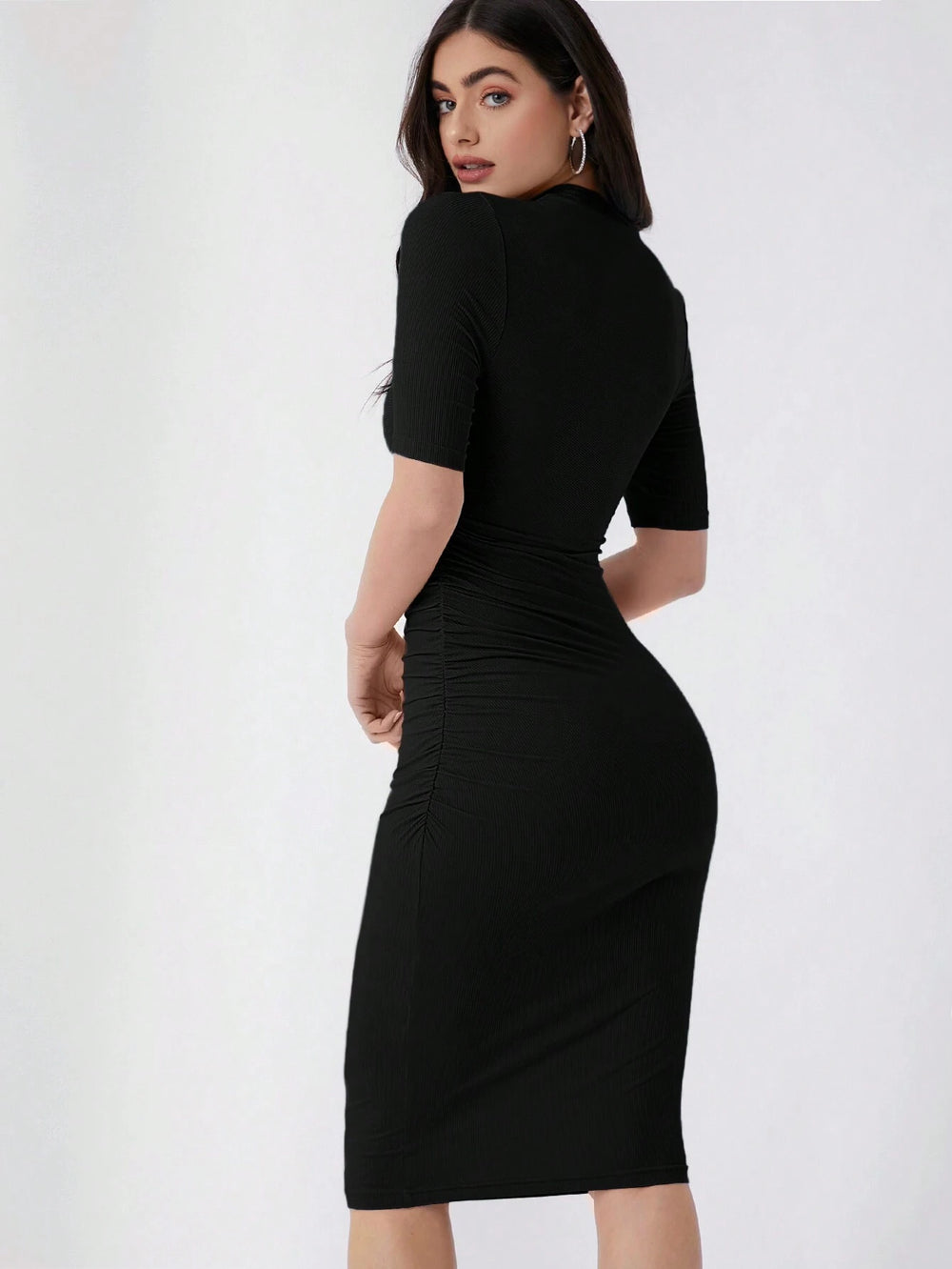 Mujer luciendo vestido negro ajustado con cuello alzado y corte lápiz.