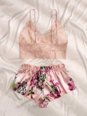 Vista completa del conjunto de pijama romántico con top de encaje y short floral sobre un fondo rosa.
