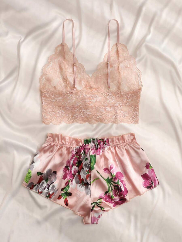 Vista completa del conjunto de pijama romántico con top de encaje y short floral sobre un fondo rosa.