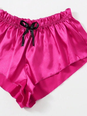 Detalle del short de pijama de satén fucsia con cintura elástica y lazo decorativo negro.