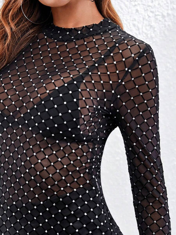 Detalle de la manga larga transparente con brillantes de una blusa negra.