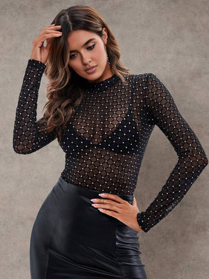 Mujer modelando una blusa de malla negra transparente con patrón geométrico de brillantes y cuello alto.