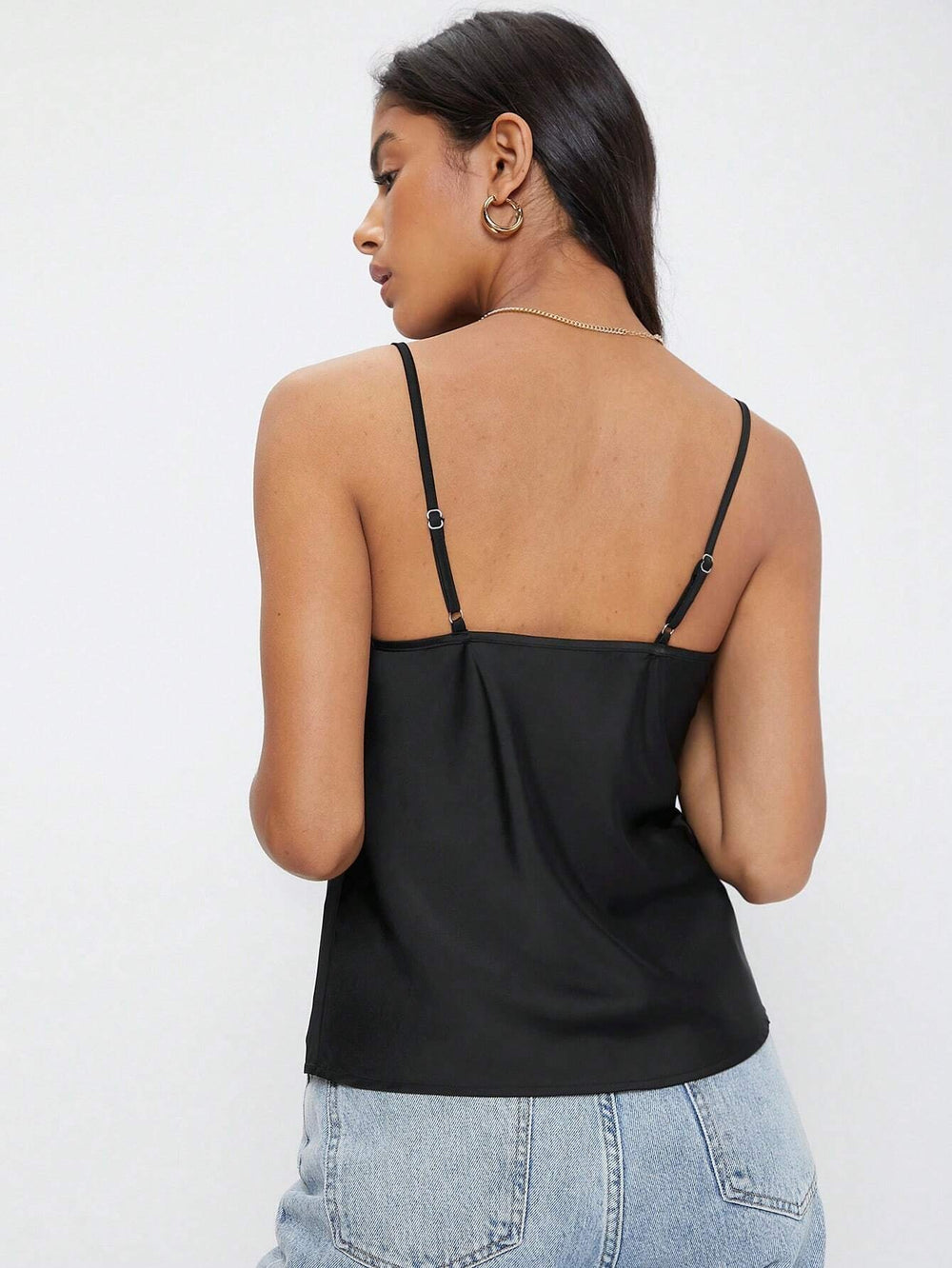 Vista frontal de la blusa negra de tirantes con diseño drapeado.